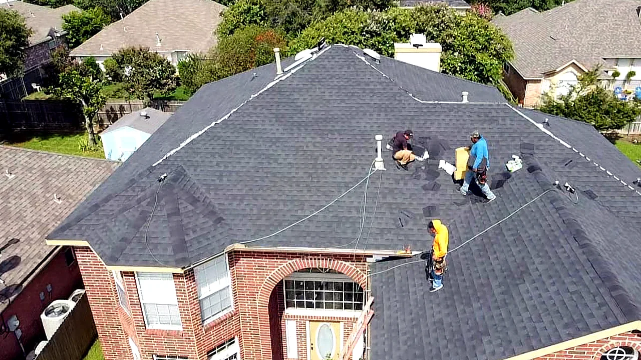 Roofing crew installing shingles on a brick two-story home